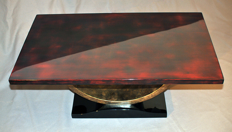 Table de style Art déco – plateau rouge et glacis bruns, piétement en laque arrachée bronze et laque noire.